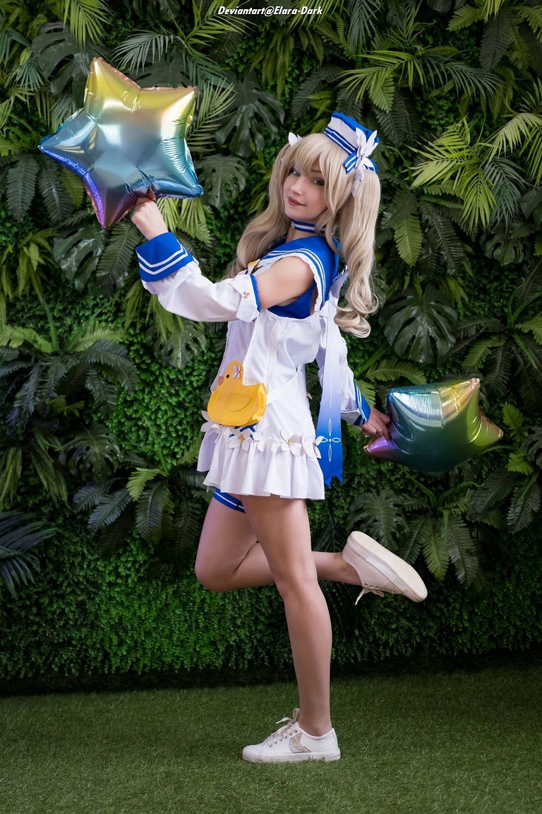 A person in a playful pose holding colorful star-shaped balloons, wearing a cute outfit with a sailor collar. The background features lush green foliage.