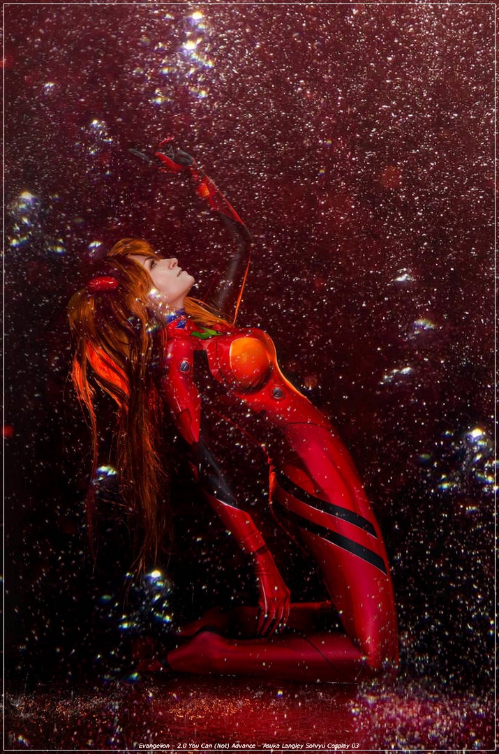 A person in a vibrant, red bodysuit resembling a character from anime, kneeling and reaching out amidst a backdrop of sparkly bubbles and a dark, shimmering surface.