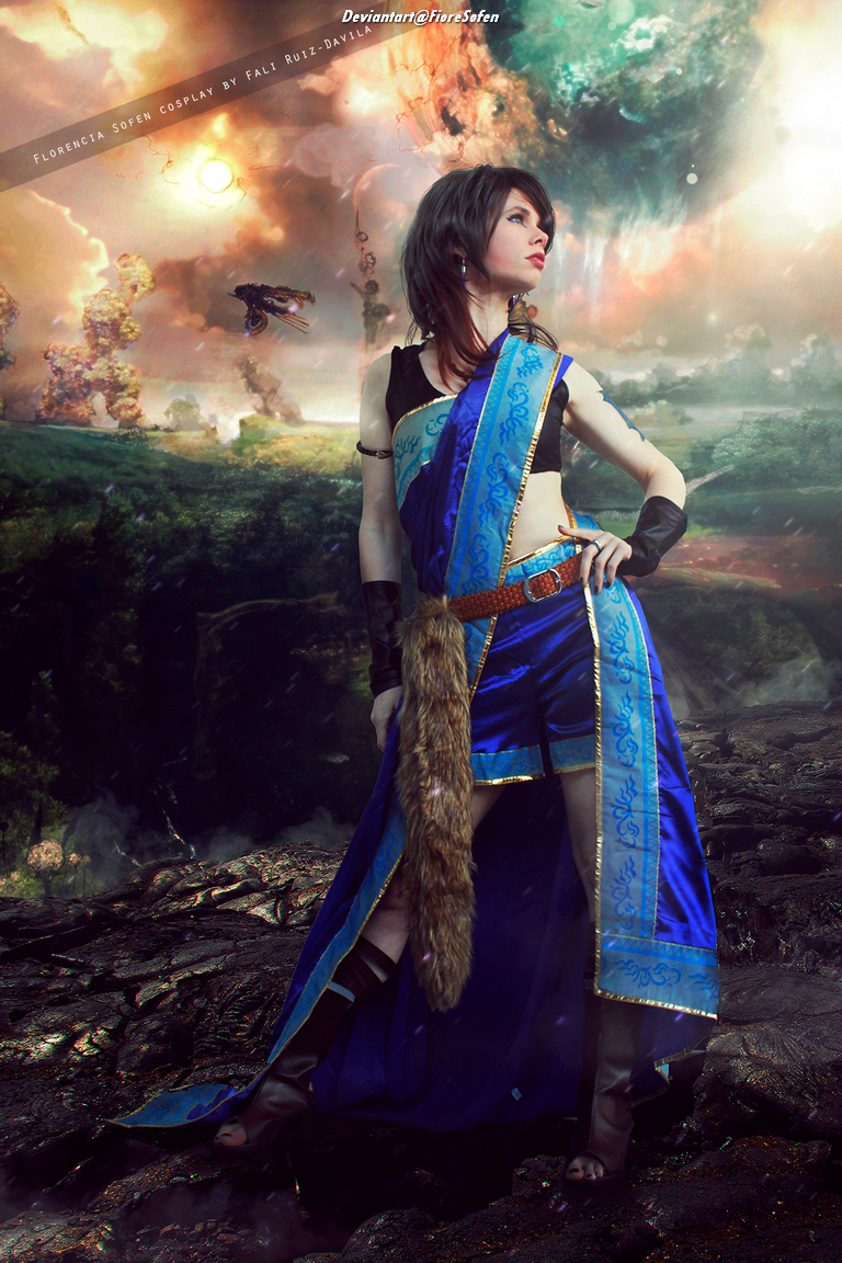 A character cosplaying as Florencia Sofen, wearing a blue and white outfit with a flowing skirt, standing in a dramatic landscape with vibrant, cosmic elements in the background.