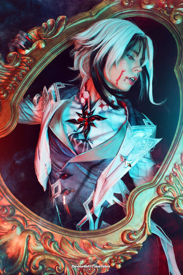 A person dressed in elaborate costume with white hair and makeup, holding an ornate gold frame. Blood is depicted on their face, creating a dramatic and eerie effect, with smoke in the background.