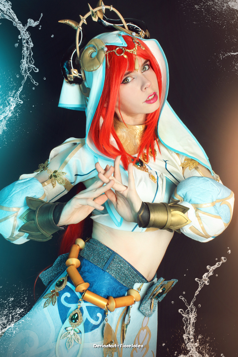 A person in a costume with red hair and elaborate accessories, posing dramatically against a dark background, with water effects around them.
