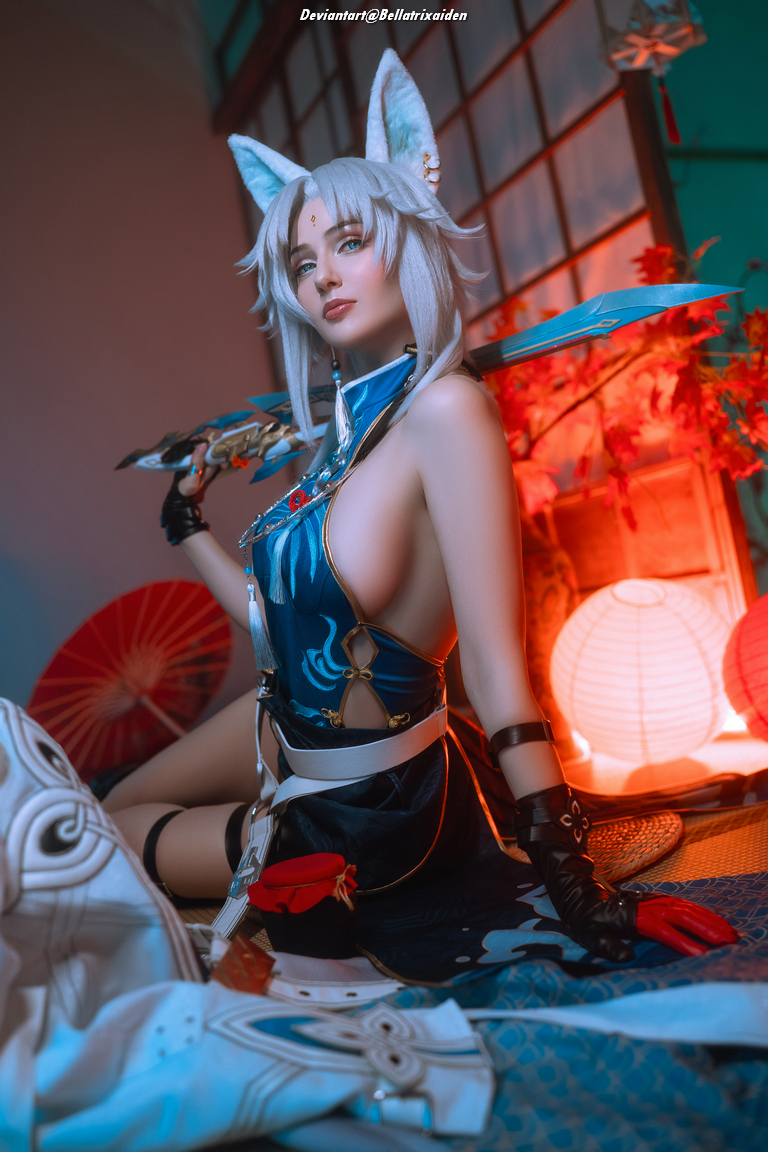 A cosplayer with fox ears poses with a sword, wearing a blue and black outfit. The background features decorative lanterns and traditional elements.
