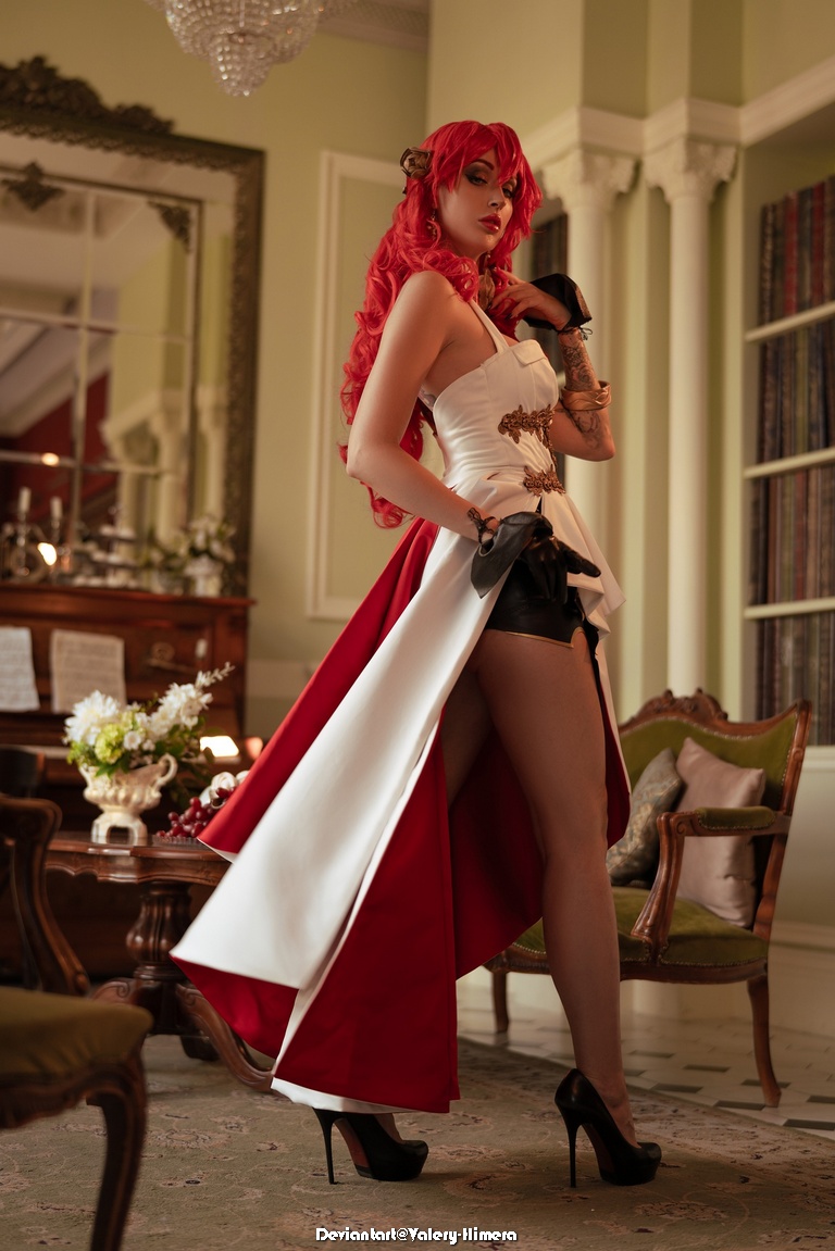 A model in a stylish costume featuring a white and red dress, posing confidently in an elegant room with vintage decor.
