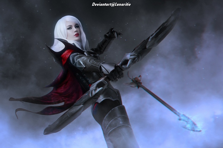 A fantasy character with long white hair, dressed in dark armor and a flowing red cape, wielding a spear against a dramatic smoky background.