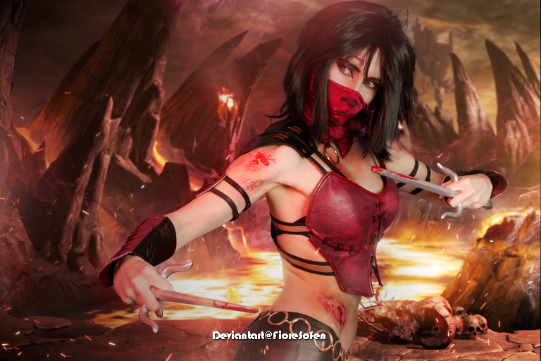 A female character in a dramatic pose, dressed in a red and black outfit with a mask and wielding blades, set against a fiery, rocky background.