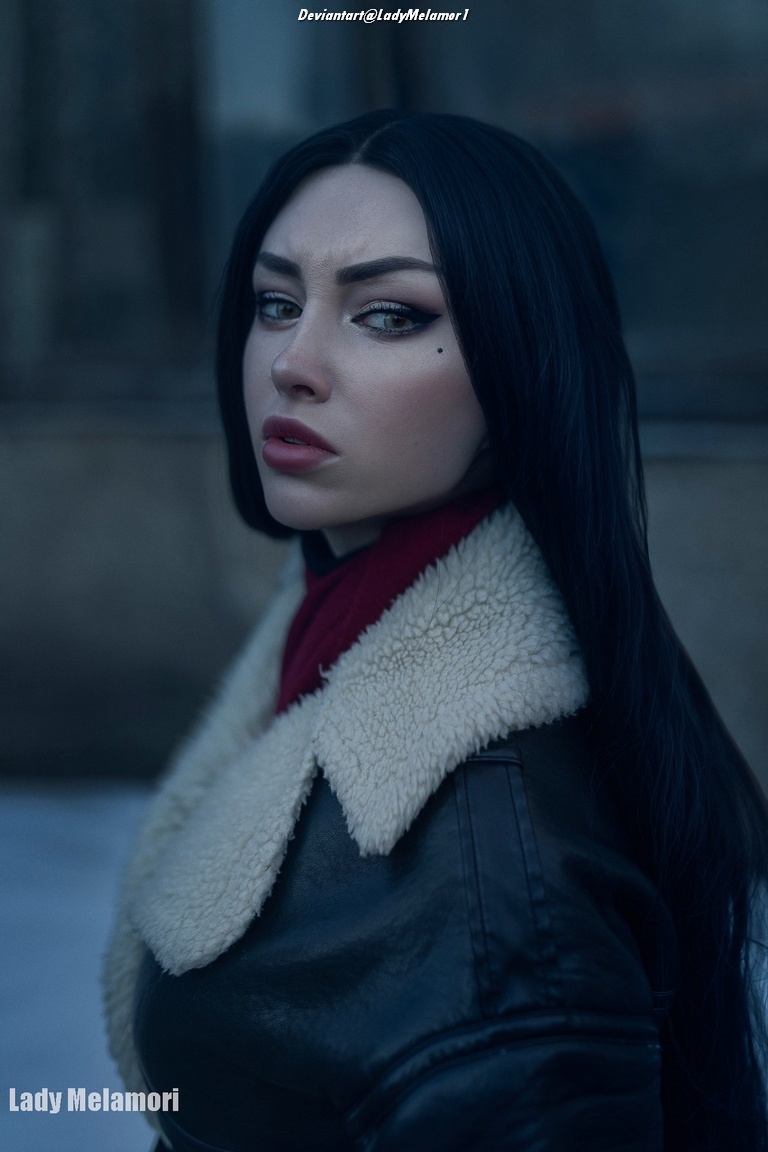 A woman with long dark hair wearing a black leather jacket and a red scarf, looking over her shoulder with a fierce expression.
