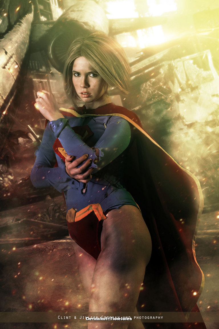 A female superhero in a costume resembling a classic comic book character, striking a powerful pose amidst a dramatic, chaotic background with a blend of light and shadow.