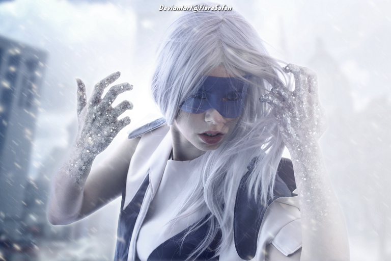 A person with long, white hair wearing a mask and futuristic clothing, surrounded by falling snow and a frosty atmosphere.