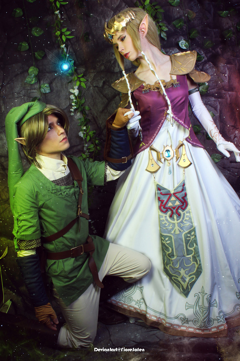 A cosplay scene featuring a male character in green attire kneeling before a female character dressed in a regal gown, captured in a mystical environment with plants and soft lighting.