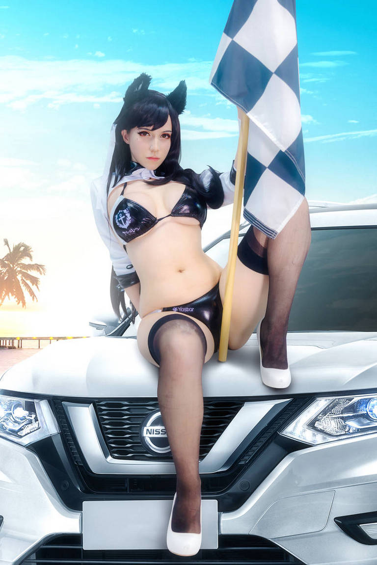 A woman dressed in a racing-themed outfit poses on the hood of a Nissan car, holding a checkered flag against a blue sky background.