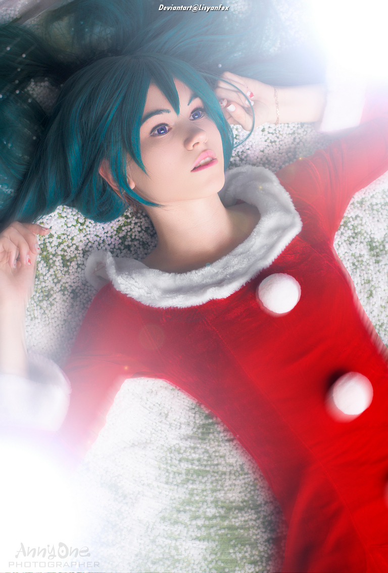 A person with teal hair wearing a red and white outfit, lying on a soft surface with a dreamy expression.