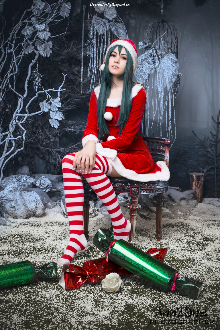 A person in a red and white Christmas outfit with striped stockings is sitting on a wooden chair surrounded by festive decorations and snow-like material on the ground.