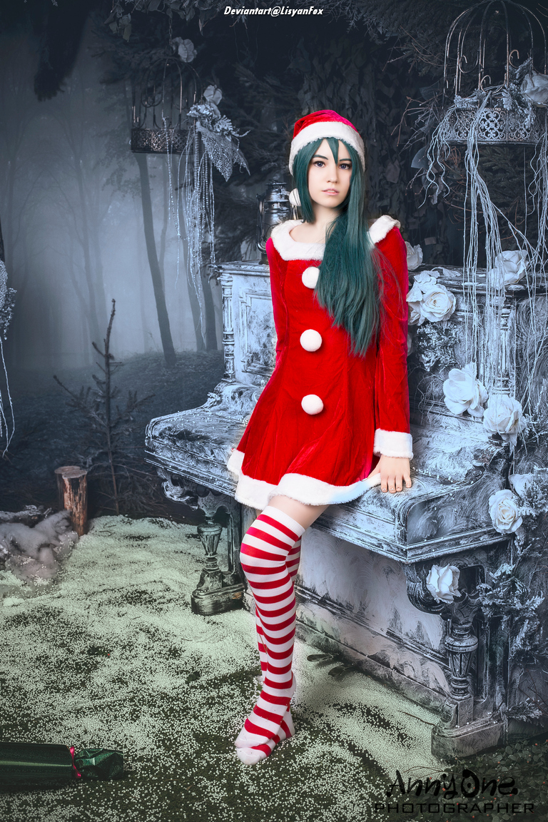 A person dressed in a red Santa Claus costume with white accents, sitting on a vintage bench in a dark, forest-like setting. The individual has long teal hair and is wearing a matching Santa hat and striped stockings.
