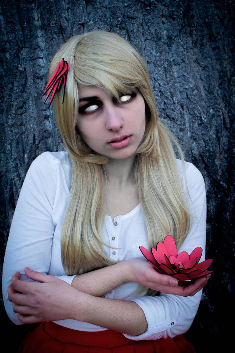 A person with long blonde hair, wearing a white shirt and a red skirt, sits against a tree. They have a solemn expression, with white eyes and red accents in their hair. They hold a pink flower in their hands.