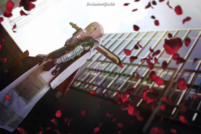 A character in cosplay holding a sword, surrounded by falling rose petals, with a modern building in the background.