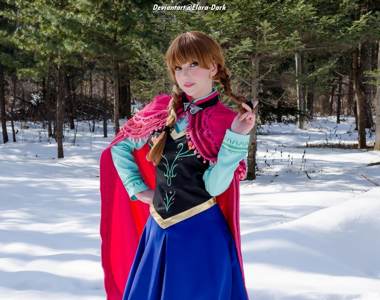 A person dressed in a colorful costume inspired by a character from a popular animated movie, standing in a snowy forest setting.