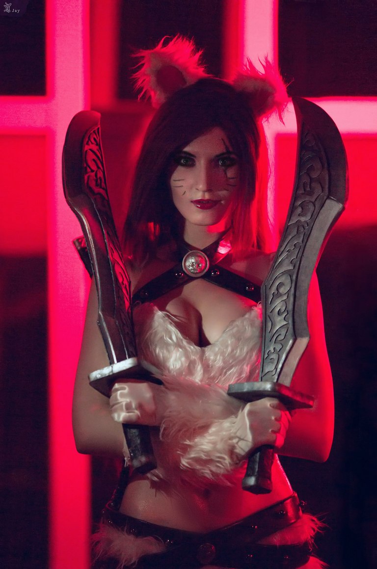 A character cosplaying as a cat-themed warrior, holding two ornate swords, set against a red glowing background.