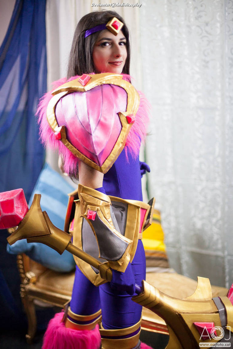 A person in a colorful costume resembling a fantasy character, with a pink shield and golden armor details, posing confidently.