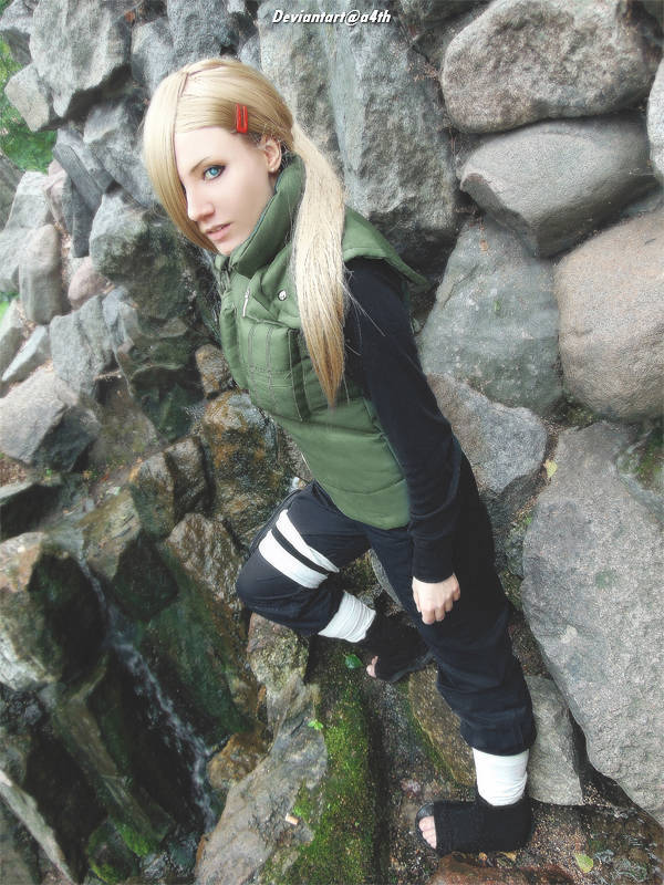 A character resembling a ninja on a rocky landscape, dressed in a green vest and black clothing, with long blonde hair and striking eyes.