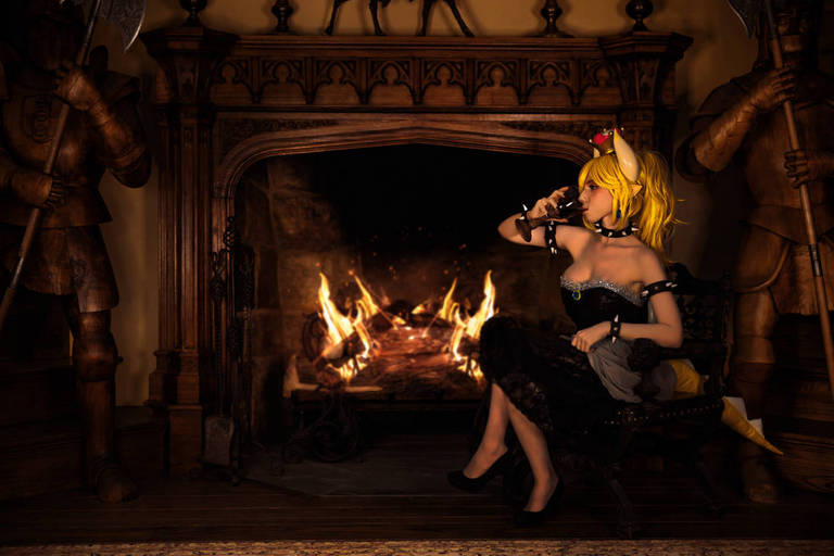 A character with fox ears and blonde hair sitting by a fireplace in a gothic-style room, wearing a black dress and holding a cup, with wooden knights in the background.
