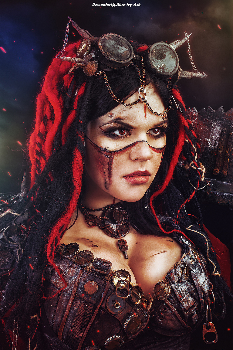 A close-up portrait of a woman with dramatic makeup and styled hair featuring red accents, wearing a steampunk-inspired outfit adorned with gears and chains.