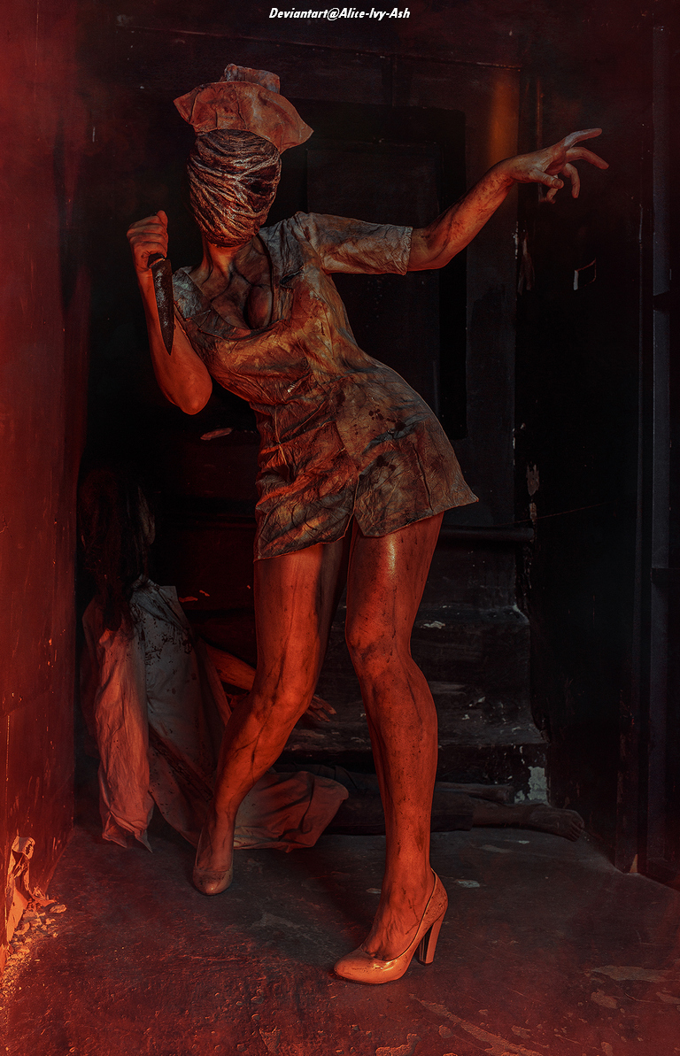 A woman dressed as a creepy nurse brandishes a knife, with her face covered in gauze. The scene is dimly lit, creating a spooky atmosphere.