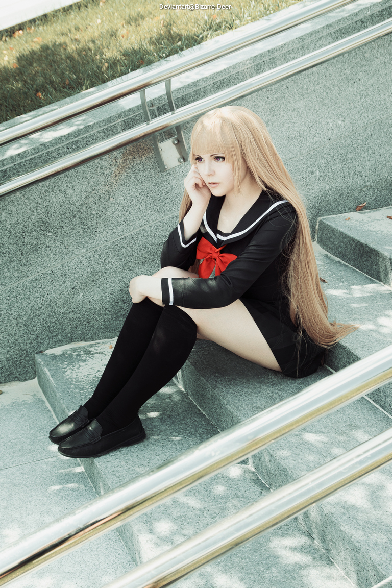 A person wearing a school uniform with a red bow sitting on stairs, looking contemplative.
