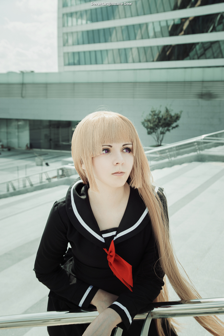 A young person with long blonde hair and purple eyes poses in a black school uniform with a red tie, leaning on a railing in an urban setting.