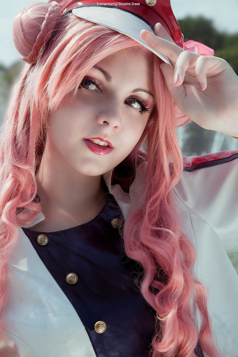 A portrait of a person with long pink hair, wearing a red and white outfit with gold buttons, holding a hat and gazing towards the camera.