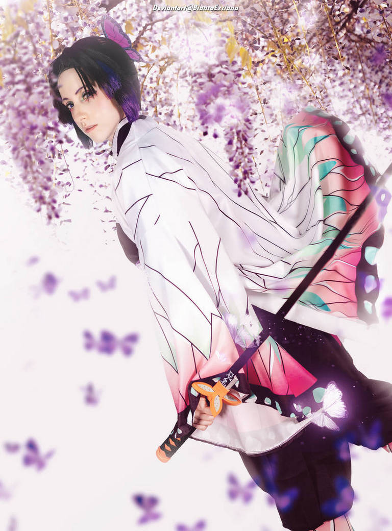 A person dressed in a colorful kimono with floral patterns, holding a sword, set against a backdrop of purple wisteria flowers and butterflies.