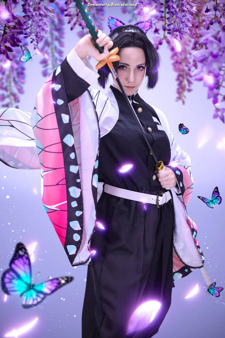 A cosplayer dressed in a colorful kimono with butterfly motifs, holding a sword and posing confidently amidst purple flowers and butterflies.
