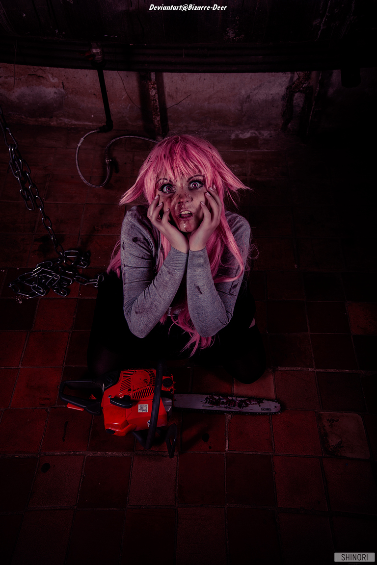 A person with pink hair sits on the floor, surrounded by chains, with a distressed expression and their hands on their face. A chainsaw lies on the ground next to them.