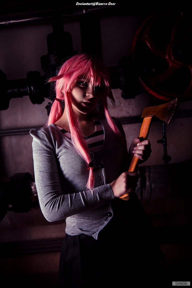 A person with pink hair, wearing a gray cardigan and holding a wooden axe, stands against a backdrop of industrial pipes and machinery.
