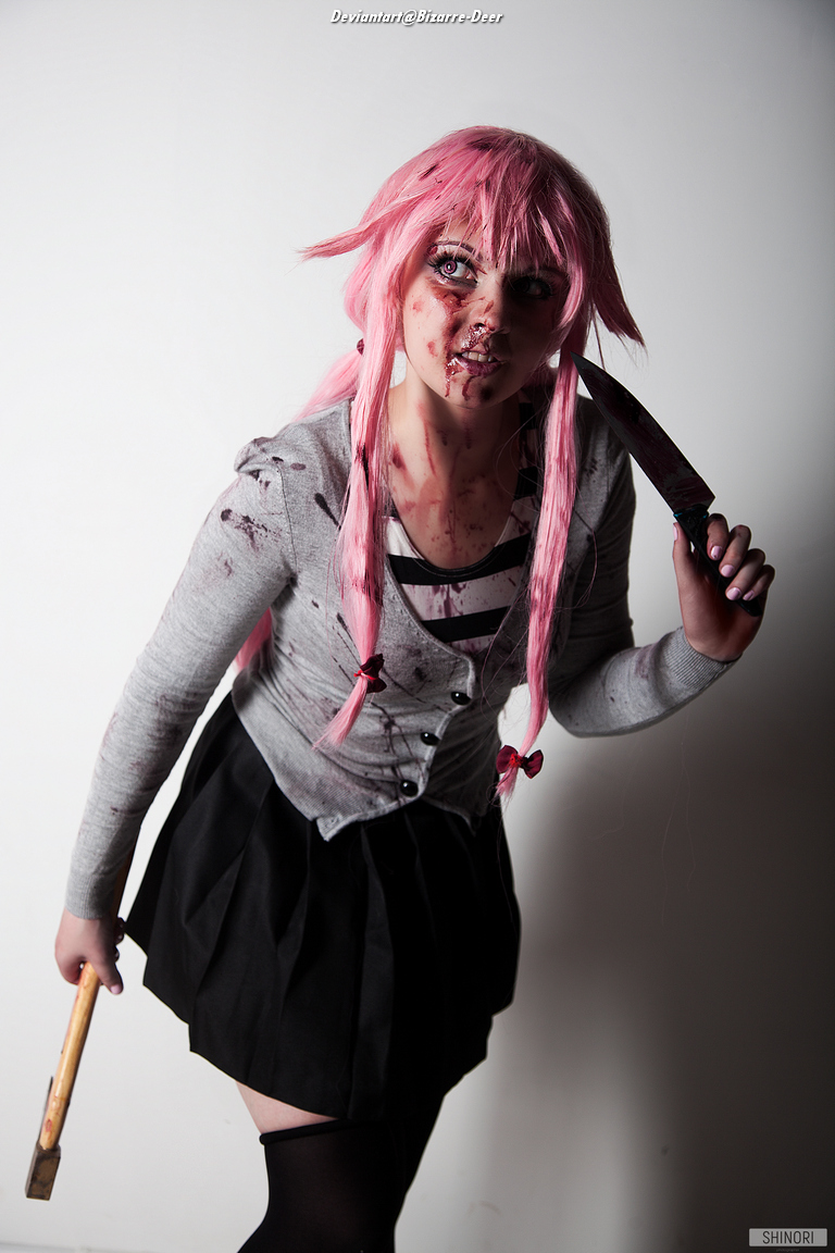 A person with pink hair wearing a blood-stained gray cardigan and black skirt, holding a knife and a hammer, posing dramatically against a plain background.