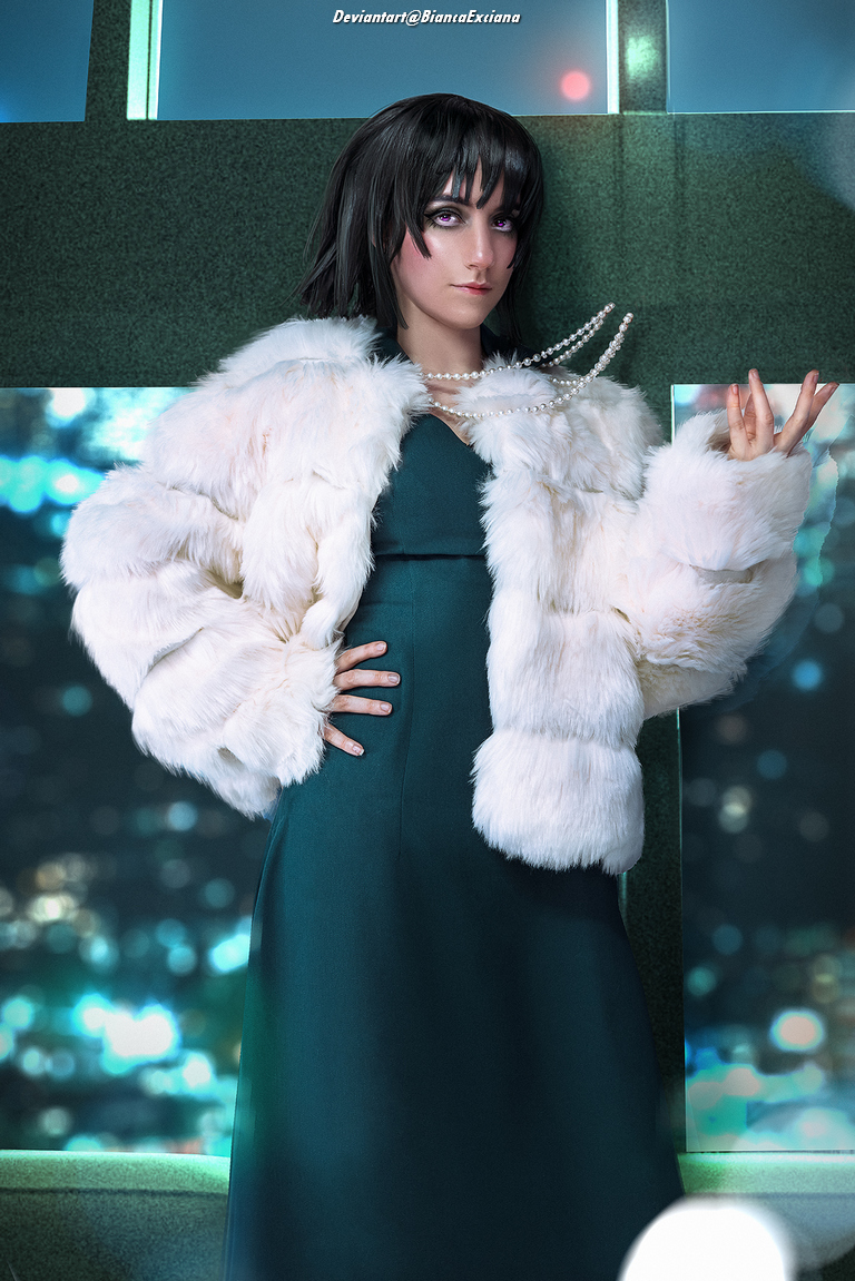 A person poses confidently in a luxurious fur coat over a sleek green dress, accessorized with pearls, set against a sparkling background.