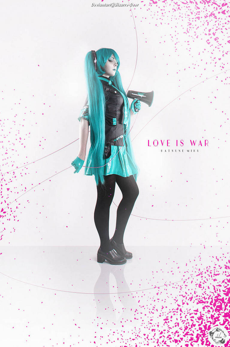 A cosplayer dressed as Hatsune Miku, featuring long teal hair and a black outfit, holding a toy microphone against a white background with pink splatter designs, with the text 'LOVE IS WAR' displayed.