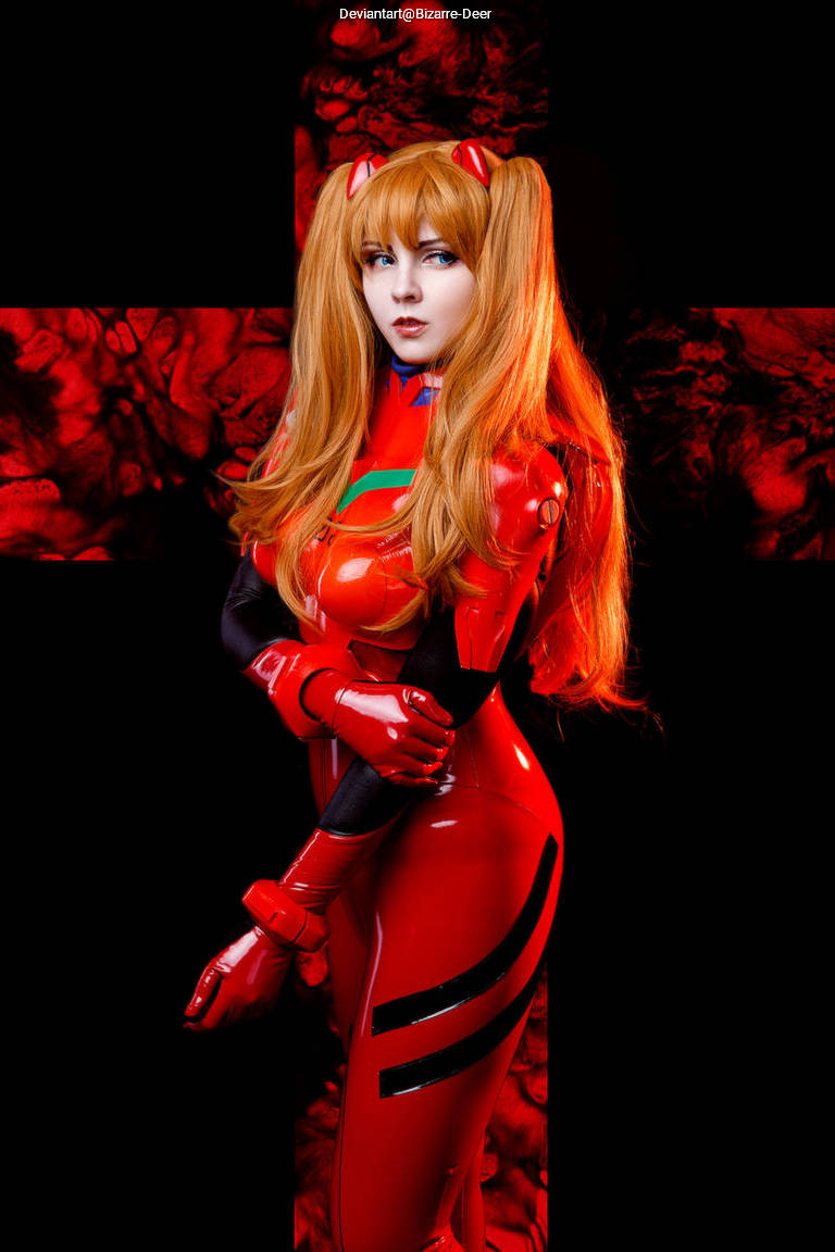 A person in a red bodysuit with black accents and orange hair, posing against a dark background with a red cross design.