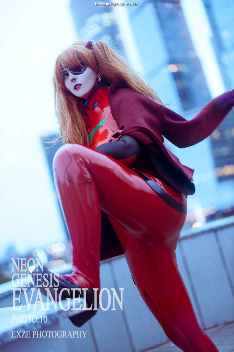 A person dressed in a red and black cosplay outfit resembling a character from Neon Genesis Evangelion, striking a dynamic pose against an urban backdrop.