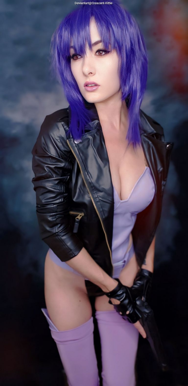 A person with purple hair wearing a black leather jacket and holding a gun, posing confidently against a blurred background.