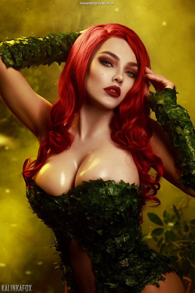 A person with long red hair dressed in a green leafy costume, striking a pose against a vibrant yellow background.