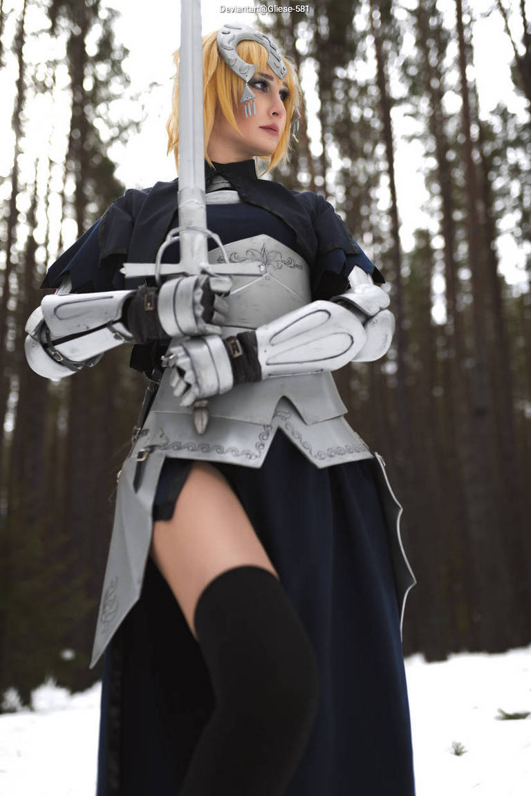 A person in a detailed costume holds a sword, standing confidently in a snowy forest environment.