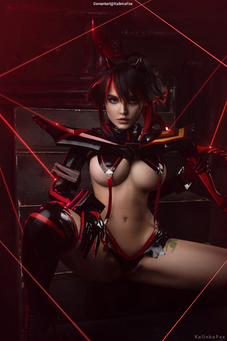 A female cosplayer wearing a striking black and red futuristic outfit, sitting on a staircase with red light effects creating a dramatic atmosphere.