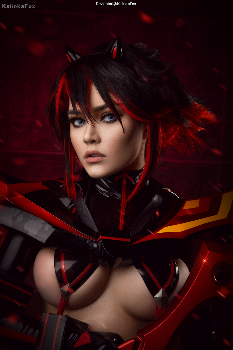 A person dressed in a detailed and vibrant cosplay costume featuring black and red colors, with dramatic makeup and striking hair styled in spikes. The background is dark, enhancing the boldness of the outfit.