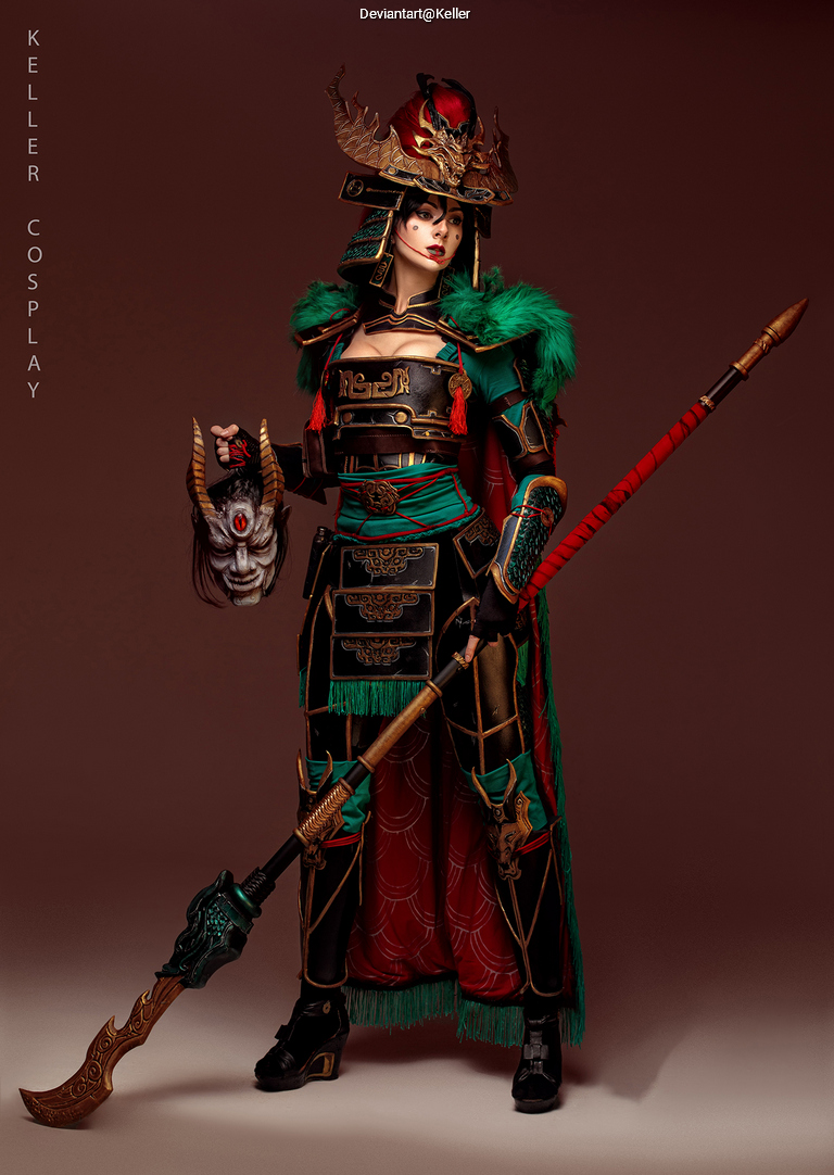 A person dressed in elaborate cosplay attire, featuring intricate armor, a helmet with horns, and a spear, showcasing vibrant colors and detailed patterns.