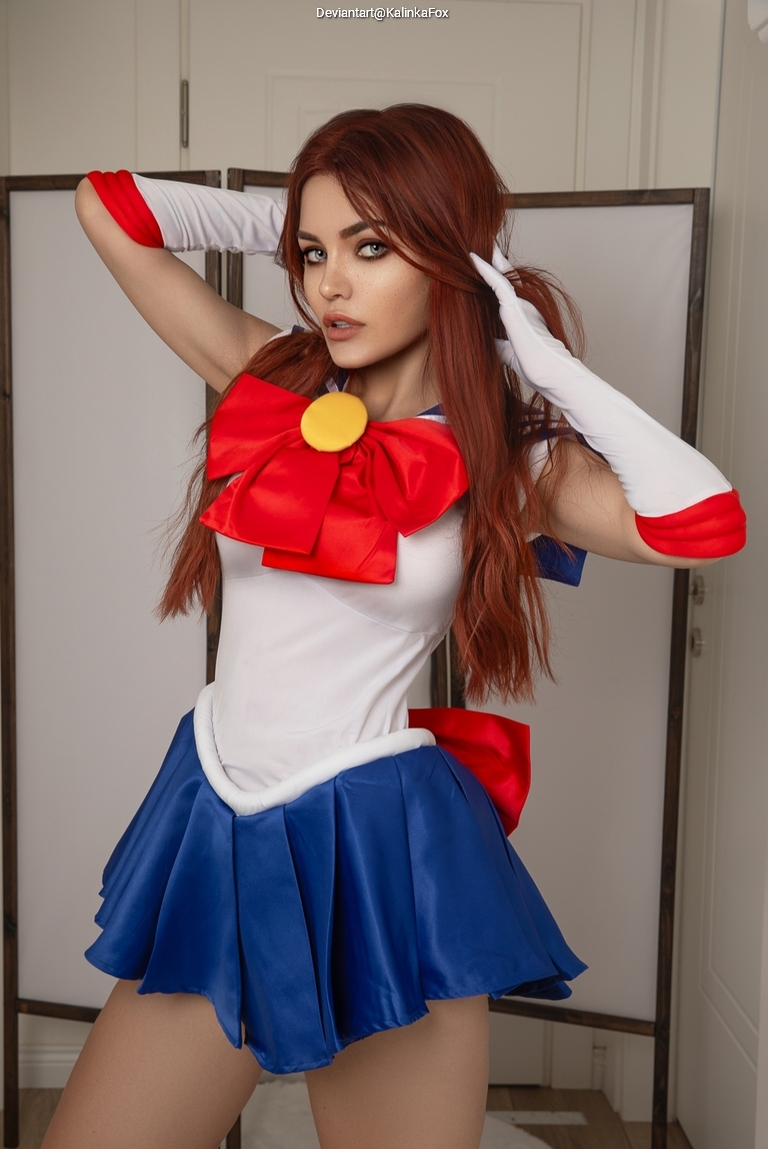A person dressed in a colorful sailor-themed costume with a large red bow and blue skirt strikes a playful pose indoors.