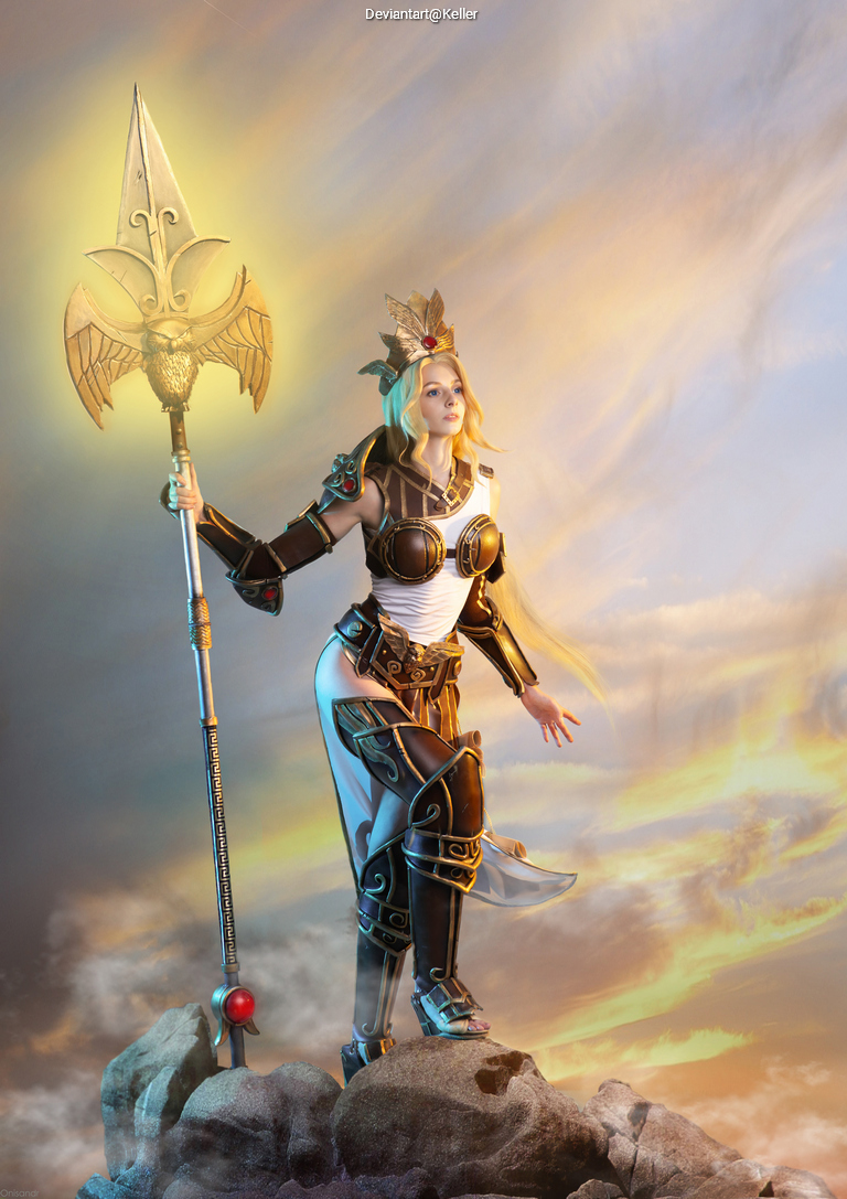 A warrior woman in ornate armor stands on a rock, holding a spear with a golden tip and a regal crown, set against a dramatic sky.