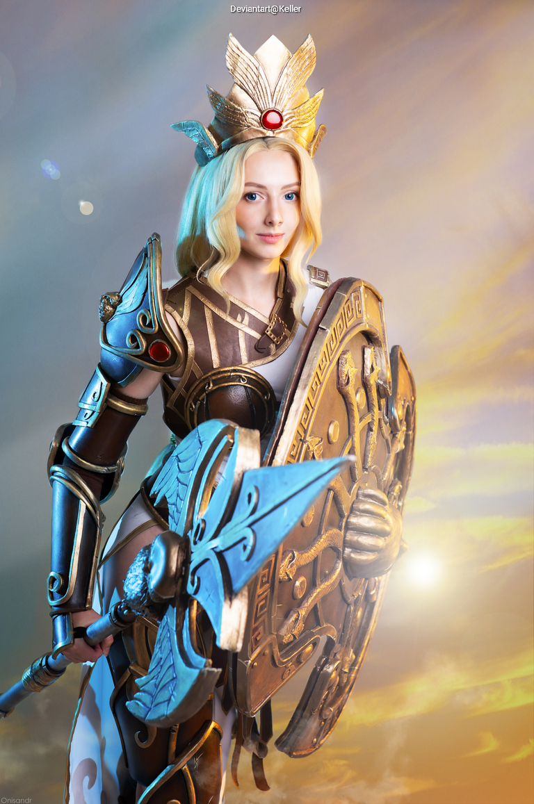 A woman dressed in elaborate armor and a crown, holding a shield and an axe, set against a colorful, ethereal background.
