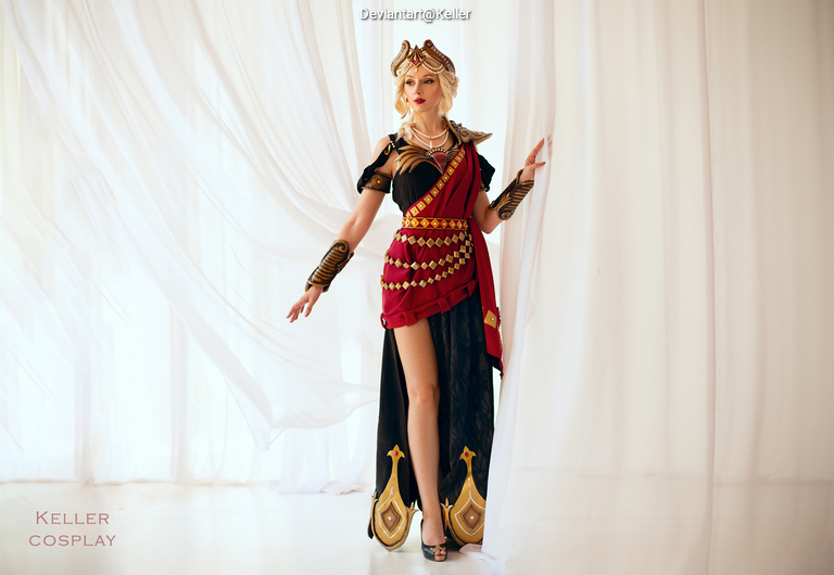 A woman in an elaborate costume resembling a historical warrior, featuring intricate gold and red details, stands gracefully against a light backdrop.