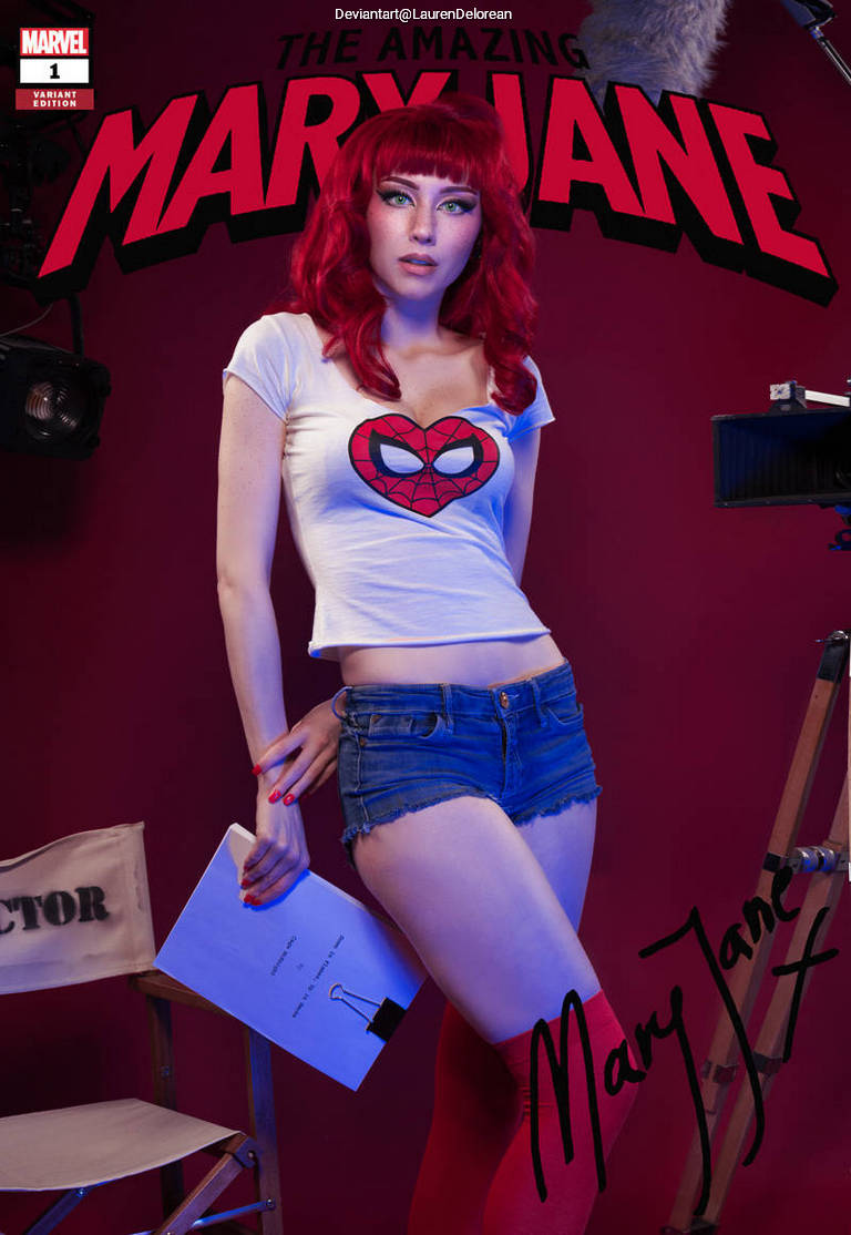 A woman with red hair wearing a Spider-Man t-shirt and denim shorts, posing with a clipboard in front of a red backdrop. The setting appears to be a photo shoot with studio lights visible.