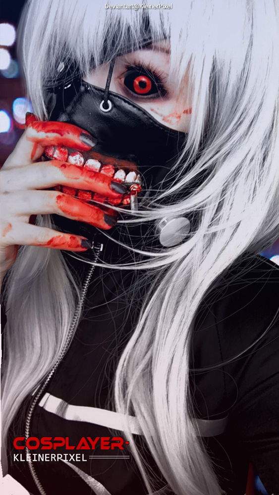 A person in elaborate makeup and costume, featuring long white hair and a black mask, with red accents and a grotesque hand gesture depicting bloodied fingers and a skeletal mouth design.